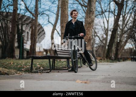 Lächelnder junger Mann, der im Herbst eine Fahrradtour in einem grünen Park macht Stockfoto