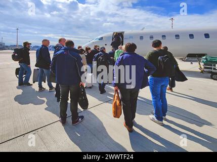 Passagiere mit Handgepäck, die in einem kleinen Flugzeug auf dem Rollfeld am Flughafen Düsseldorf, Deutschland, Nordrhein-Westfalen, Niederrhein, Düsseldorf steigen Stockfoto