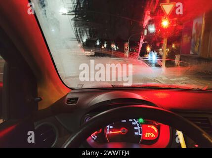 Blick aus dem Auto bei gefährlich schlechter Sicht bei Nacht mit Regen vor einer roten Ampel, Deutschland Stockfoto