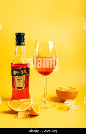 Wladiwostok, Russland - 21. Februar 2024: Flasche Aperol Aperitivo Sommer-Cocktail mit Glas mit Spritz-Cocktail und Orangen auf hellgelbem Stockfoto