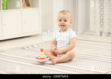 Kinderspielzeug. Süßer kleiner Junge und drehbares Top auf Teppich zu Hause Stockfoto