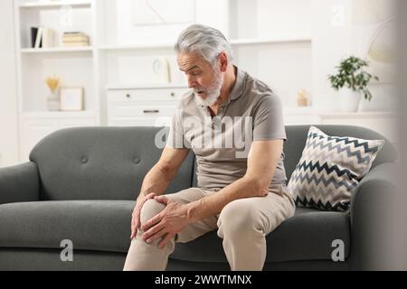 Arthritis-Symptome. Mann mit Schmerzen im Knie zu Hause Stockfoto