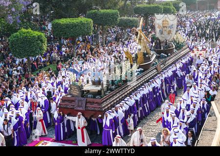 Antigua, Guatemala. März 2024. Katholische Pönitenten umgeben den massiven Prozessionswagen, der während der 20-stündigen Palmensonntag-La Reseña-Prozession, die den Beginn der Karwoche am 24. März 2024 in Antigua, Guatemala, markiert, auf den zentralen Platz einzieht. Die opulenten Prozessionen, detailgetreuen Alfombras und jahrhundertealten Traditionen ziehen mehr als 1 Million Menschen in die alte Hauptstadt. Quelle: Richard Ellis/Richard Ellis/Alamy Live News Stockfoto