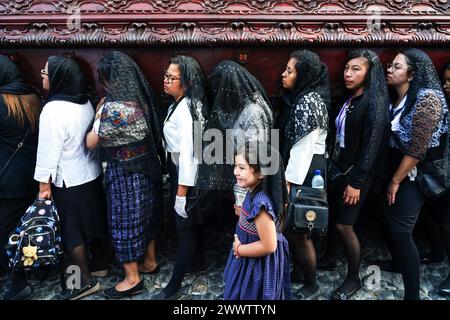 Antigua, Guatemala. März 2024. Ein junges Mädchen lächelt, als sie zusammen mit ihrer Mutter und anderen Bußfrauen den gewaltigen Prozessionswagen auf dem Central Plaza während der Palmensonntag-La-Reseña-Prozession, die den Beginn der Karwoche am 24. März 2024 in Antigua, Guatemala, markiert, trägt. Die opulenten Prozessionen, detailgetreuen Alfombras und jahrhundertealten Traditionen ziehen mehr als 1 Million Menschen in die alte Hauptstadt. Quelle: Richard Ellis/Richard Ellis/Alamy Live News Stockfoto