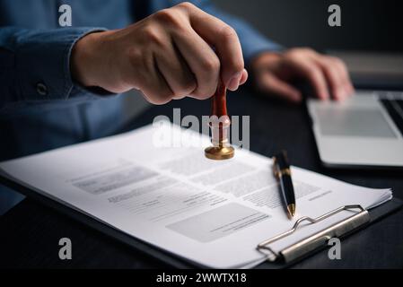 Mann stempelt die Genehmigung auf Finanz-, Bank- oder Anlageunterlagen an seinem Schreibtisch. Kautschukstempel mit Vertragsrecht und Geschäftsdokum Stockfoto