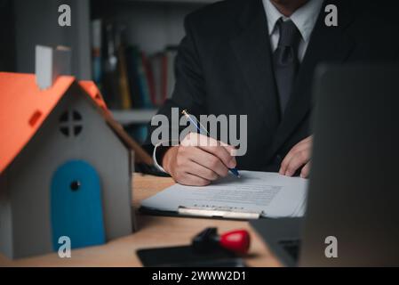 Ein professioneller Immobilienmakler unterzeichnet Dokumente oder Verträge, die den Kauf einer Immobilie genehmigen. Versicherungs- oder Hausrechtsverträge Stockfoto