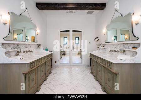 Bad mit Doppelwaschbecken, beleuchteten Spiegeln darüber Stockfoto