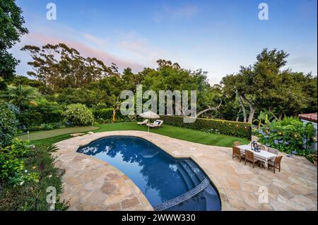 Eine Oase im Hinterhof mit Swimmingpool, üppigem Grün und Gartenmöbeln Stockfoto