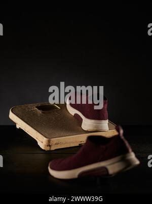 Schuhe auf einer Waage, die lange Zeit nicht getragen wurden, sind durch Staub und anderen Schmutz vor dunklem Hintergrund sichtbar Stockfoto