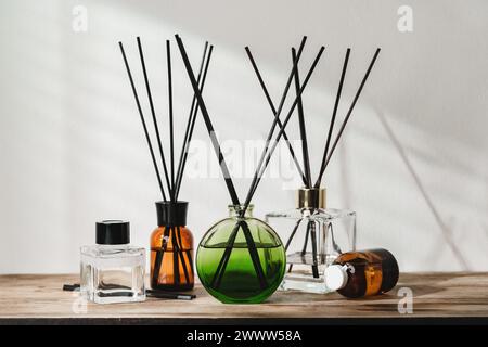 Eine Sammlung aromatischer Schilfdiffusoren auf einem Holztisch vor neutralem Hintergrund Stockfoto