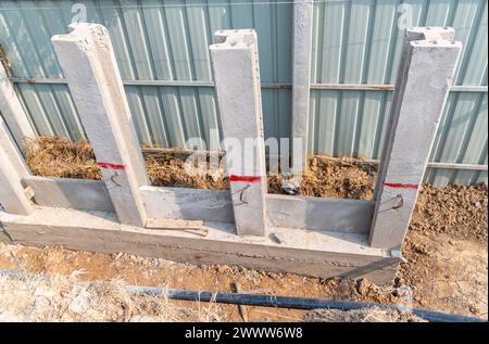 Bau einer Stützwand mit Pfahl- und Fertigbetonplatten auf der Baustelle. Stockfoto