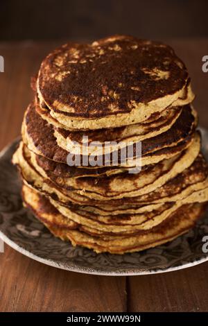 Ein Haufen Eiweißbananen- und Haferflockenpfannkuchen auf einem rustikalen Holzbrett Stockfoto