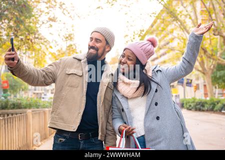 Multiethnisch lächelndes junges Paar, das draußen Selfie auf dem Handy macht. Stockfoto