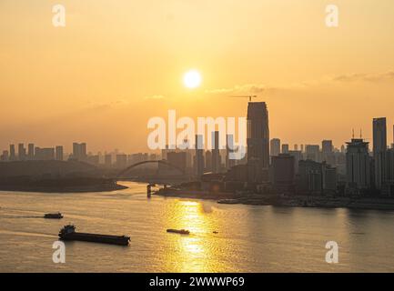 Bei Sonnenuntergang stehen Brücken und Gebäude auf beiden Seiten des Yangtse-Flusses, mit Schiffen, die auf der Flussoberfläche segeln Stockfoto