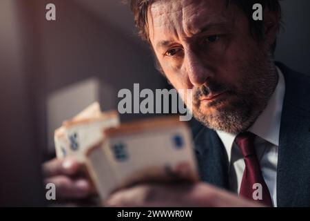 Nahaufnahme eines Geschäftsmannes, der Euro-Banknoten zählt, Bargeld spät in der Nacht im Büro, selektiver Fokus Stockfoto