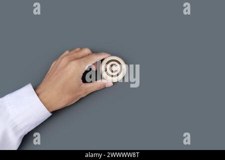 Die Hand eines Geschäftsmannes trägt ein hölzernes Abzeichen mit eingraviertem Copyright-Symbol. Schutzrechte und Markenpatentschutz im Geschäftskonzept. Stockfoto