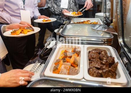 Die Teilnehmer des Business Seminars wählen während der Mittagspause in einem Selbstbedienungs-Buffetrestaurant Speisen aus Stockfoto