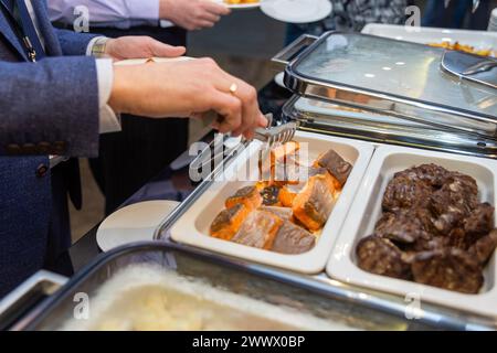 Die Teilnehmer des Business Seminars wählen während der Mittagspause in einem Selbstbedienungs-Buffetrestaurant Speisen aus Stockfoto