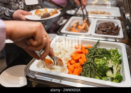 Die Teilnehmer des Business Seminars wählen während der Mittagspause in einem Selbstbedienungs-Buffetrestaurant Speisen aus Stockfoto