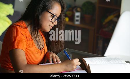 Eine junge Frau, die an einem Tisch sitzt und studiert Stockfoto