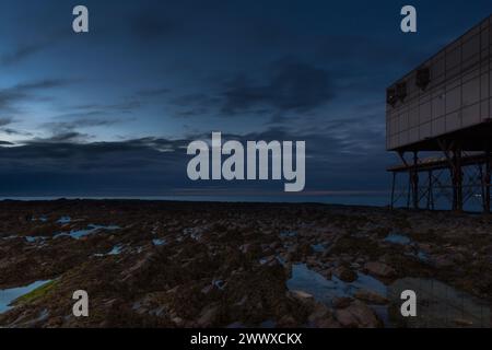 Dämmerungsbild der Felsen des Piers im Vordergrund neben dem Royal Pier in Aberystwyth, Wales, Großbritannien mit Blick auf die Cardigan Bay Stockfoto