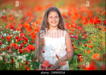 Hübsches kleines Mädchen in weißem Kleid im Sommer blühenden Mohn Feld zu Fuß unter der Abendsonne Stockfoto