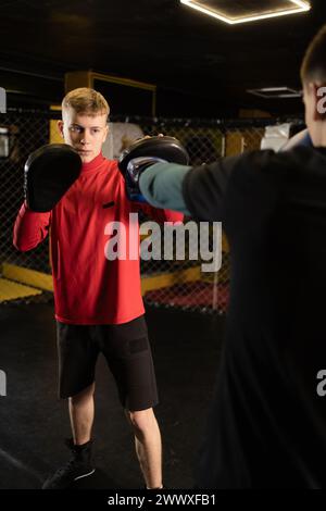 Zwei junge männliche Boxer, die im Fitnessstudio am Ring trainieren. Boxen und gesunder Lebensstil Stockfoto