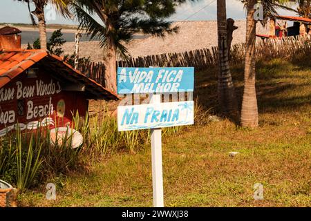 Strohdächer von Bars und Restaurants, am Strand von Barreiro, Camocim, Ceará, Nordosten Brasiliens, und das Schild mit dem Satz: das Leben ist besser am Strand Stockfoto