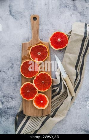 Grapefruit auf Akazienholz Schneidebrett mit Leinenserviette und Messer Stockfoto