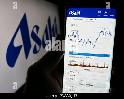 Person, die ein Handy hält, mit Website des japanischen Brauunternehmens Asahi Group Holdings Ltd. Vor dem Logo. Konzentrieren Sie sich auf die Mitte des Telefondisplays. Stockfoto