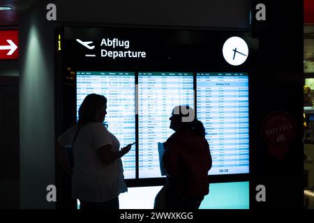 Zwei Reisende, die an der Abfahrtstafel am Flughafen Wien schauen Stockfoto