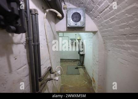 26. März 2024, Sachsen, Kšnigstein: Eine Schaufensterpuppe mit Schutzanzug und Gasmaske steht in einer Ecke während des Presserundgangs der neuen Ausstellung 'Nuklearbunker und Pulvermagazin' im ehemaligen Bunker für den DDR-Zivilschutz. Die Festung Königstein macht Räume des einst geheimen DDR-Bunkers im Festungswald, die in der Ausstellung selten zu sehen sind, im Rahmen von Führungen zugänglich. Foto: Robert Michael/dpa Stockfoto