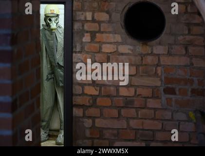 26. März 2024, Sachsen, Kšnigstein: Eine Schaufensterpuppe mit Schutzanzug und Gasmaske steht in einer Ecke während des Presserundgangs der neuen Ausstellung 'Nuklearbunker und Pulvermagazin' im ehemaligen Bunker für den DDR-Zivilschutz. Die Festung Königstein macht Räume des einst geheimen DDR-Bunkers im Festungswald, die in der Ausstellung selten zu sehen sind, im Rahmen von Führungen zugänglich. Foto: Robert Michael/dpa Stockfoto