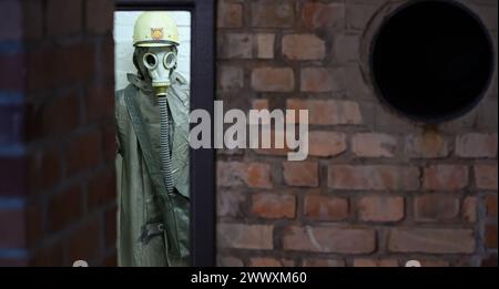 26. März 2024, Sachsen, Kšnigstein: Eine Schaufensterpuppe mit Schutzanzug und Gasmaske steht in einer Ecke während des Presserundgangs der neuen Ausstellung 'Nuklearbunker und Pulvermagazin' im ehemaligen Bunker für den DDR-Zivilschutz. Die Festung Königstein macht Räume des einst geheimen DDR-Bunkers im Festungswald, die in der Ausstellung selten zu sehen sind, im Rahmen von Führungen zugänglich. Foto: Robert Michael/dpa Stockfoto