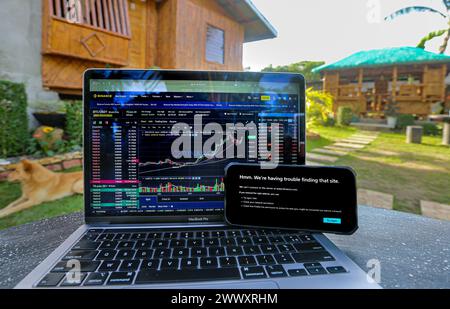 Manila, Philippinen. 26. März 2024: Binance-Website noch auf Laptop mit Telekommunikationsbetreiber Converge zugänglich, aber bereits von seinem Konkurrenten PLDT auf Smartphone verboten, vor dem traditionellen philippinischen Bambushaus 'Bahay Kubo'. Securities & Exchange Commission (SEC) ordnete philippinische Internetdienstanbieter an, den Kryptowährungsriesen Binance.com zu blockieren. Im Jahr 2017 hatte Duterte admin eine ähnliche Verbotsanordnung bezüglich populärer Websites für Erwachsene erlassen. Eine Zensur, die kein Ergebnis erwartet hatte: Seither ist die PH mit VPN immer in den Top-Ländern von Pornhub Stockfoto