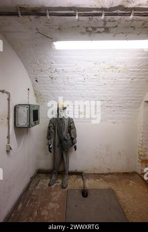 26. März 2024, Sachsen, Königstein: Eine Schaufensterpuppe mit Schutzanzug und Gasmaske steht in einer Ecke während des Presserundgangs zur neuen Ausstellung „Kernbunker und Pulvermagazin“ im ehemaligen Bunker für den Zivilschutz der DDR. Die Festung Königstein macht Räume des einst geheimen DDR-Bunkers im Festungswald, die in der Ausstellung selten zu sehen sind, auf Führungen zugänglich. Foto: Robert Michael/dpa Stockfoto