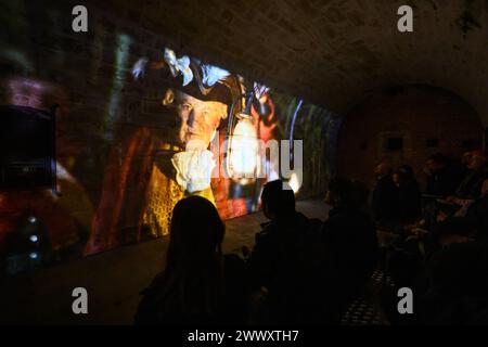26. März 2024, Sachsen, Königstein: Teilnehmer der Pressetour der neuen Ausstellung Atomic Bunker and Powder Magazine sehen sich im Bullet Magazine No. 2 einen Kurzfilm mit dem Titel Time Travel Powder Magazine an. Die Festung Königstein macht Räume des einst geheimen DDR-Bunkers im Festungswald, die in der Ausstellung selten zu sehen sind, im Rahmen von Führungen zugänglich. Foto: Robert Michael/dpa Stockfoto