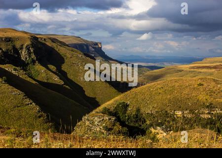 Dramatischer Blick am späten Nachmittag auf die grasbewachsenen Hänge der Drakensberg Mountains in Südafrika Stockfoto