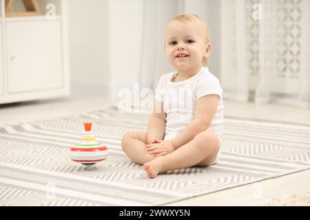 Kinderspielzeug. Süßer kleiner Junge und drehbares Top auf Teppich zu Hause Stockfoto