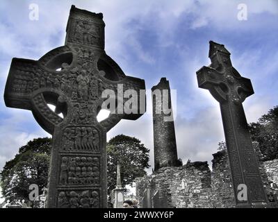 Zwei keltische Kreuze vor antiken Ruinen unter bewölktem Himmel, möglicherweise in Irland Stockfoto