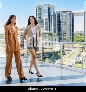 Zwei Geschäftsfrauen holen sich beim Spaziergang auf ihrer Büroterrasse auf Stockfoto