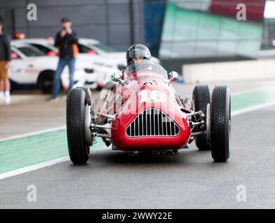 Julia de Baldanza fuhr ihr Red, Alta Grand Prix Auto durch die internationale Boxengasse, bevor das HGPCA vor dem Grand prix Cars Race 66 startet. Stockfoto