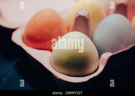 Farbig gefärbte Ostereier in rosa Karton selektiv weich fokussiert. Makrodetails von Feiertagsessen auf einem Tisch. Pastellfarben für Frühlingsferien. Stockfoto