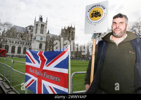 Ein Unterstützer hält ein Plakat mit der Aufschrift ëFairness for British Farmingí neben einer gewerkschaftsflagge mit der Aufschrift ëBack British Farmersí während der Demonstration auf dem Parlamentsplatz. Die Bauern versammelten sich und fuhren mit mehr als 130 Traktoren auf dem Parlamentsplatz, um zu demonstrieren, dass die britische Nahrungsmittelproduktion nicht unterstützt wird. Stockfoto