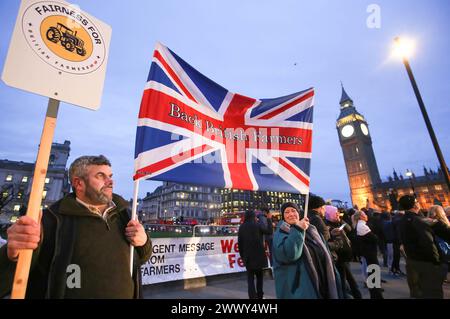 London, Großbritannien. März 2024. Ein Unterstützer hält ein Plakat mit der Aufschrift „ëFairness for British Farmingí“ neben einer gewerkschaftsflagge, die während der Demonstration die britischen Bauern unterstützt. Die Bauern versammelten sich und fuhren mit mehr als 130 Traktoren auf dem Parlamentsplatz, um zu demonstrieren, dass die britische Nahrungsmittelproduktion nicht unterstützt wird. (Foto von Martin Pope/SOPA Images/SIPA USA) Credit: SIPA USA/Alamy Live News Stockfoto