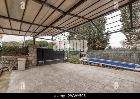 Überdachte Terrasse auf einem Einfamilienhaus mit einem Leinendach auf einer Metallkonstruktion und einem kleinen Süßwasserpool auf einer Seite Stockfoto