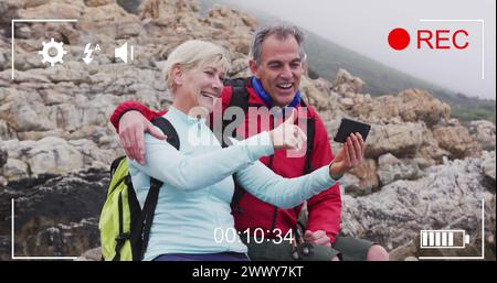 Smartphone-Bild-Interface-Bildschirm über glückliches weißes Seniorenpaar am Meer, das Selfie filmt. Aktiver Ruhestand, Kommunikation und soziale Medien Stockfoto