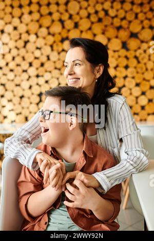 Liebe schöne Mutter, die viel Spaß mit ihrem einschließenden, fröhlichen Sohn mit Down-Syndrom im Café hat Stockfoto