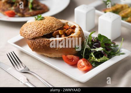 Fleischgulasch serviert in Brot auf einem weißen Teller Stockfoto