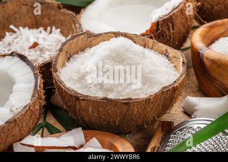 Frisch geöffnete Kokosnüsse zusammen mit Kokosscheiben, Flocken und Kokosblättern auf einem Holztisch. Schöner Hintergrund für Ihre Projekte. Stockfoto